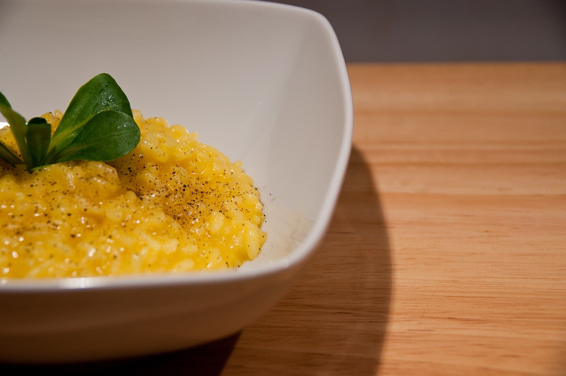 GR Stories | A bowl of golden risotto allo zafferano on a wooden table
