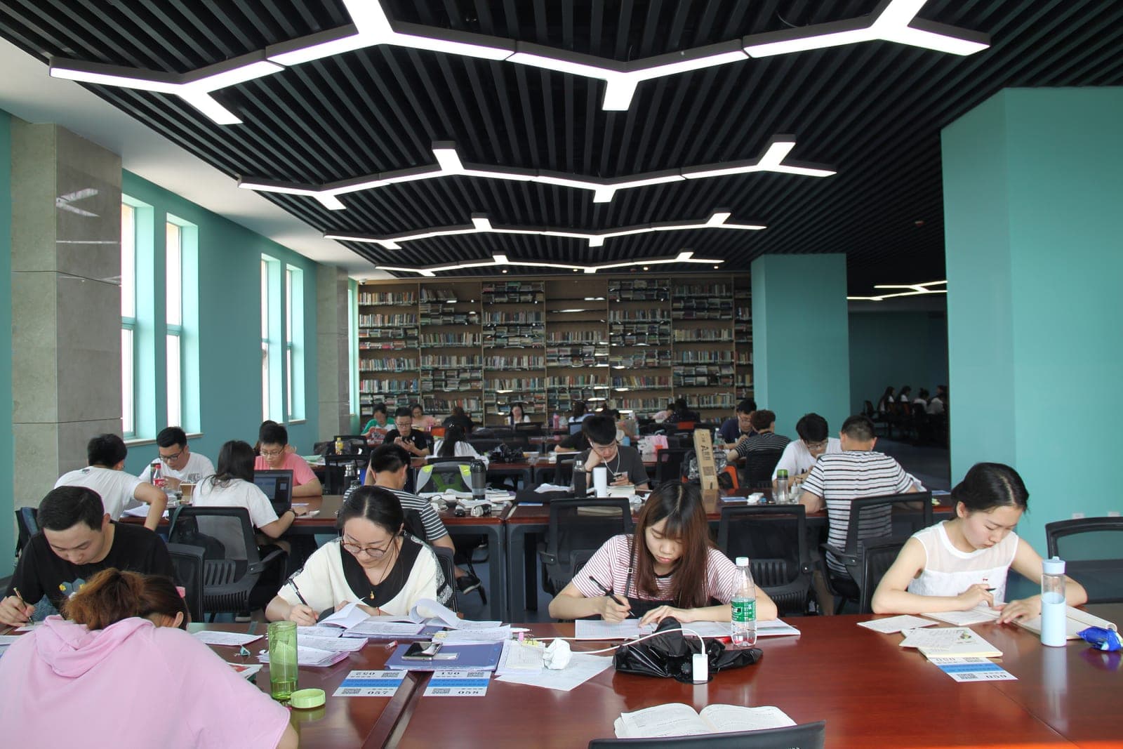 Students studying at long tables in a bright university library