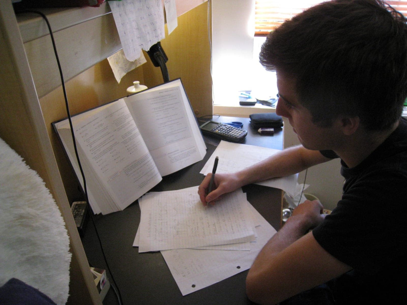GR Stories | A student working at a desk with an open textbook, calculator and handwritten notes