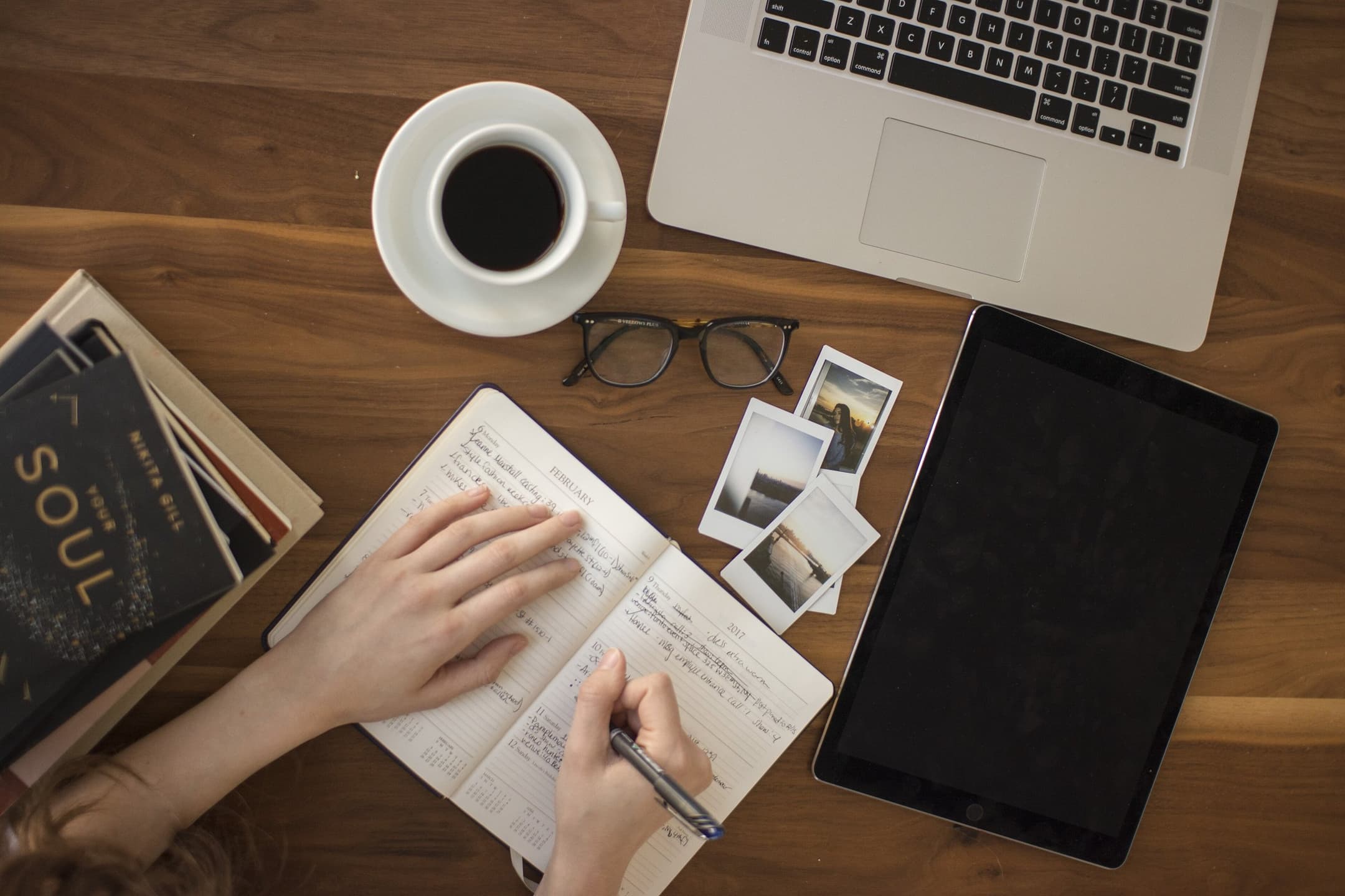 GR Stories | A notebook and a laptop on a wooden table next to a cup of coffee