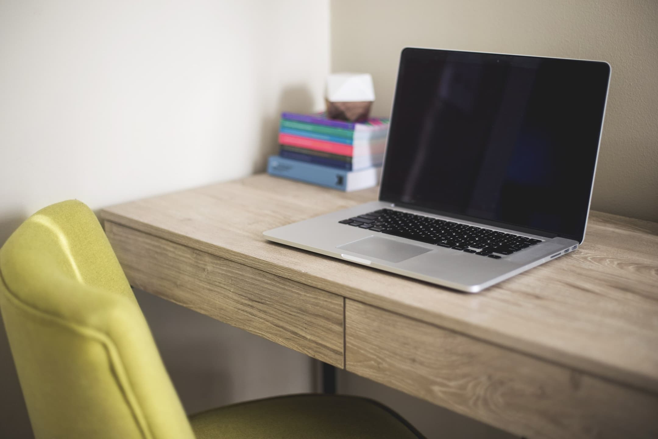 GR Stories | A laptop on a wooden desk next to a stack of books