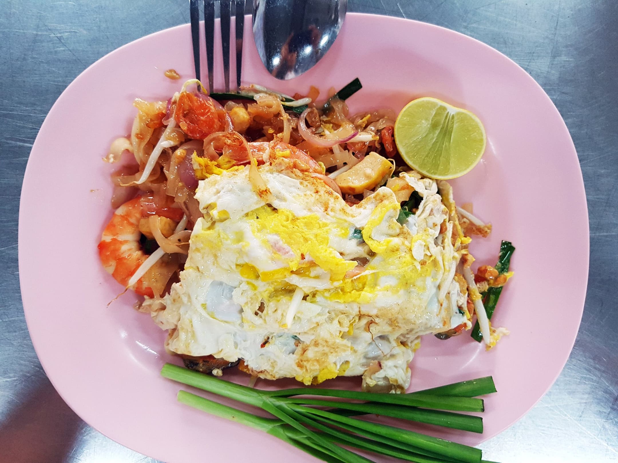 GR Stories | Pad thai with prawns, a fried egg, lime and garlic chives on a pink plate